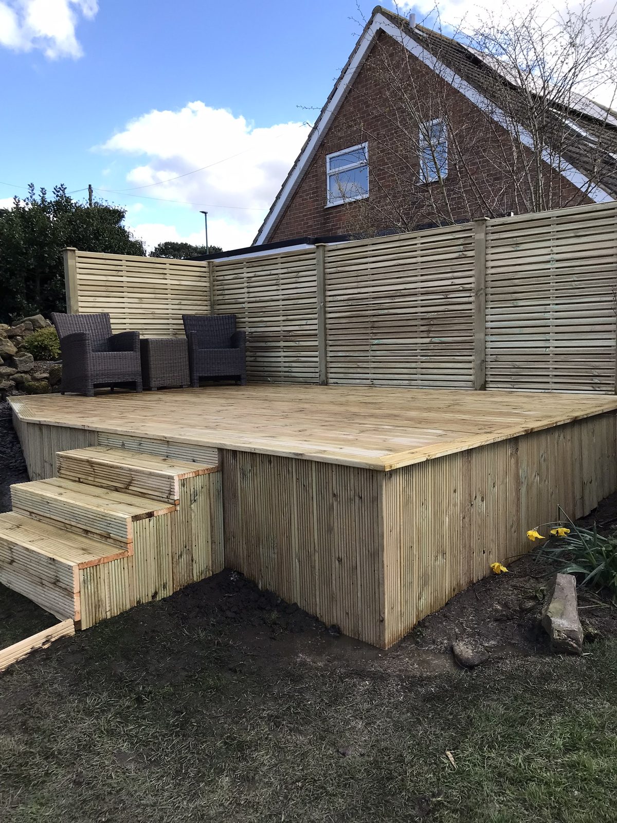 A raised timber deck with steps and a slatted privacy screen