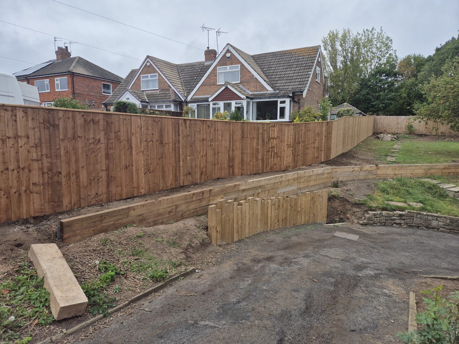 A long run of new close-board timber fencing with sleeper edging along a garden
