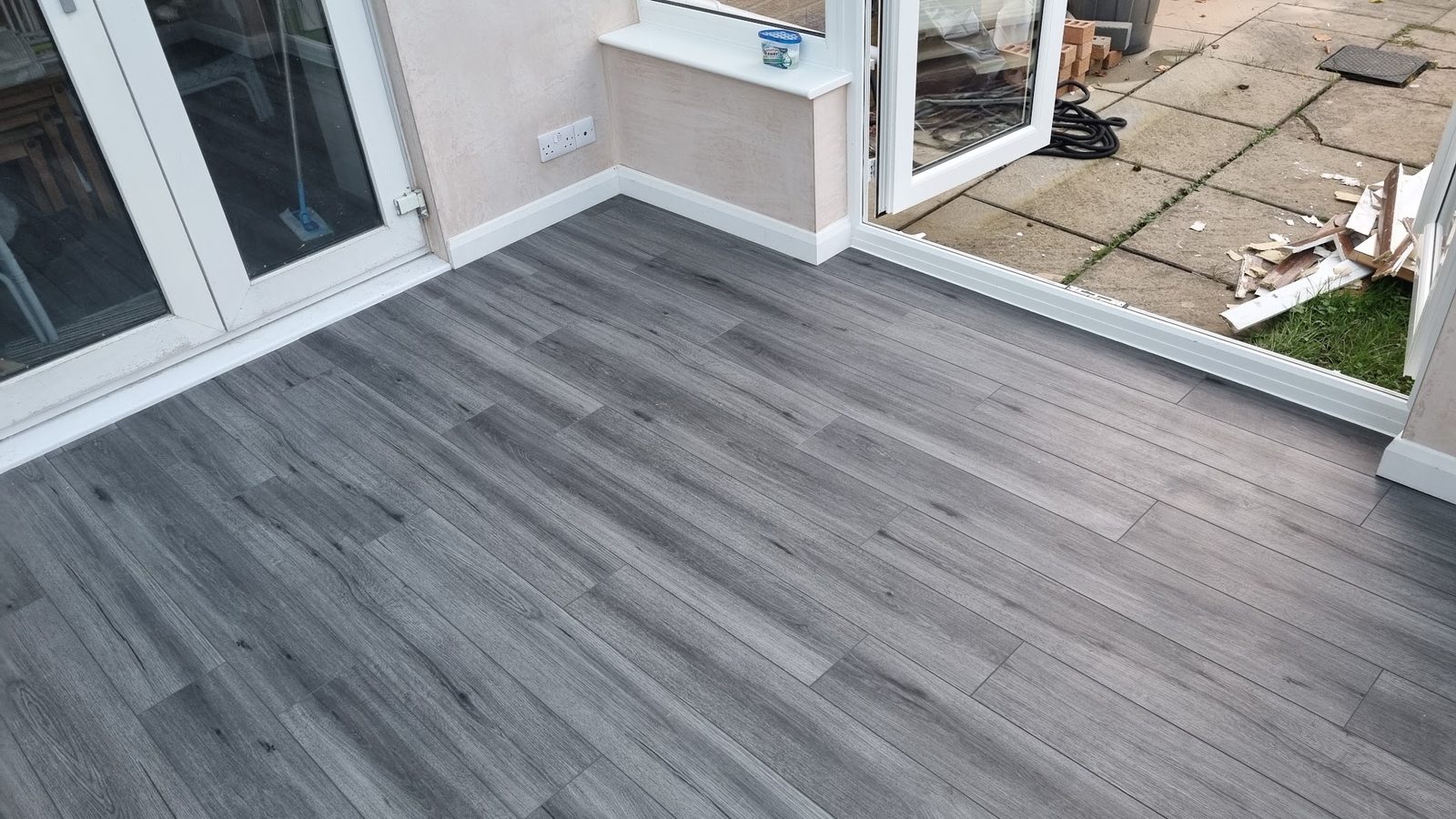 New grey plank flooring laid in a bright room with patio doors