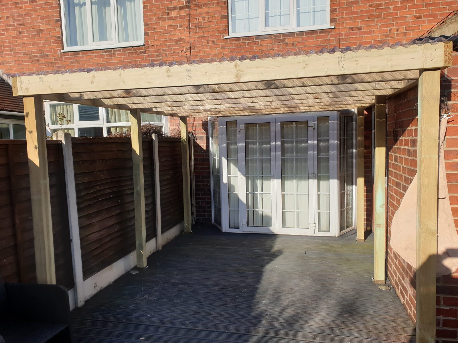 A timber pergola built over a rear patio against a brick house