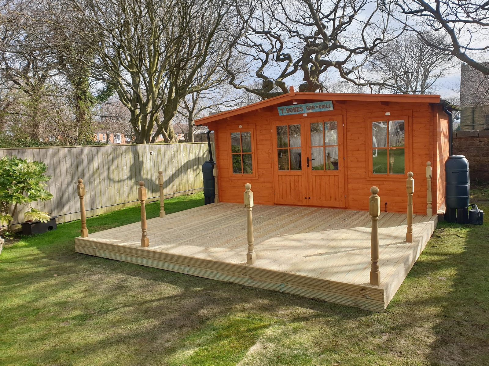 A summerhouse on new timber decking with turned spindle posts in a garden
