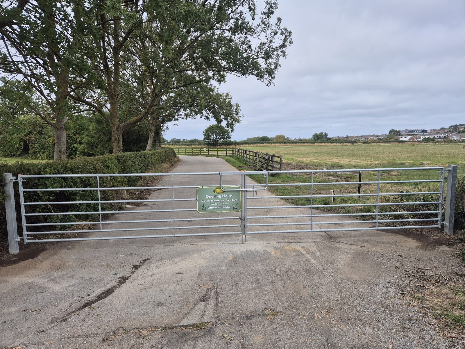 A galvanised gate across a farm track with open fields behind